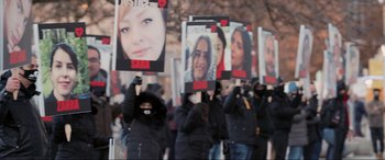 Movie still from “752 Is Not a Number” (2022), directed by Babak Payami – A group of people holding up signs with faces on them; Wide shot, High angle