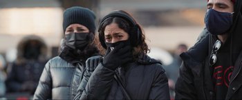Movie still from “752 Is Not a Number” (2022), directed by Babak Payami – A woman wearing ear muffs covering her face with her hands; Close Up shot, Low angle