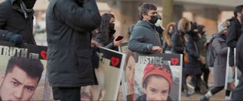 Movie still from “752 Is Not a Number” (2022), directed by Babak Payami – A group of people standing next to each other holding signs; Medium shot, High angle