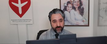 Movie still from “752 Is Not a Number” (2022), directed by Babak Payami – A man sitting in front of a computer monitor; Medium shot, Over the shoulder angle