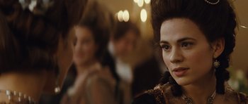 Movie still from “The Duchess” (2008), directed by Saul Dibb – A woman's face in front of other people; Close Up shot, Over the shoulder angle