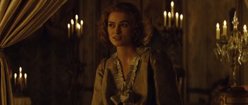 Movie still from “The Duchess” (2008), directed by Saul Dibb – A woman in a dress standing in a room with lit candles; Medium shot, Over the shoulder angle