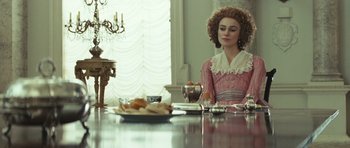 Movie still from “The Duchess” (2008), directed by Saul Dibb – A woman sitting at a table with a plate of food on the table; Medium shot, Over the shoulder angle