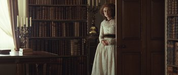 Movie still from “The Duchess” (2008), directed by Saul Dibb – A woman in a white dress standing in front of bookshelves; Medium shot, High angle
