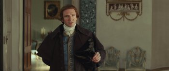 Movie still from “The Duchess” (2008), directed by Saul Dibb – A man dressed in period clothing holding a hat; Medium shot, Over the shoulder angle