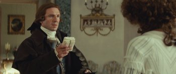 Movie still from “The Duchess” (2008), directed by Saul Dibb – A man in a period costume holding a pair of glasses; Medium shot, Over the shoulder angle