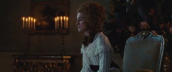 Movie still from “The Duchess” (2008), directed by Saul Dibb – A woman in a white dress sitting in front of a fireplace; Medium shot, Over the shoulder angle