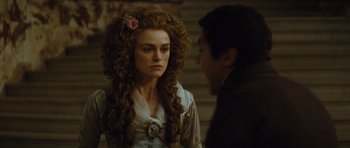 Movie still from “The Duchess” (2008), directed by Saul Dibb – A woman with long curly hair and a rose in her hair looking at a man; Close Up shot, Over the shoulder angle