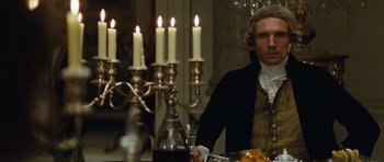 Movie still from “The Duchess” (2008), directed by Saul Dibb – A man sitting in front of a table with candles; Medium shot, Over the shoulder angle