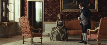 Movie still from “The Duchess” (2008), directed by Saul Dibb – A woman sitting on a chair in a room; Wide shot, High angle