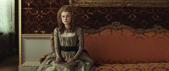 Movie still from “The Duchess” (2008), directed by Saul Dibb – A woman sitting on top of a couch wearing a dress; Medium shot, High angle