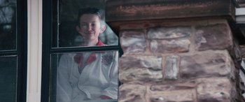 Movie still from “8-Bit Christmas” (2021), directed by Michael Dowse – A young boy is looking out of a window; Medium shot, Low angle