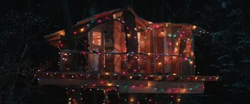 Movie still from “8-Bit Christmas” (2021), directed by Michael Dowse – A person standing on a deck with christmas lights on it; Extreme Wide shot, High angle