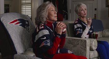 Movie still from “80 for Brady” (2023), directed by Kyle Marvin – An older woman sitting on a couch with her eyes closed; Medium shot, High angle