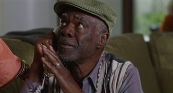 Movie still from “80 for Brady” (2023), directed by Kyle Marvin – An older man wearing a green hat and a striped vest; Close Up shot, Over the shoulder angle