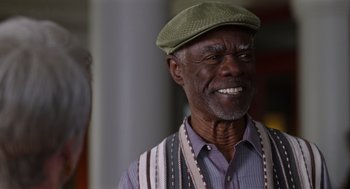 Movie still from “80 for Brady” (2023), directed by Kyle Marvin – An older man wearing a green hat and a striped vest; Close Up shot, Over the shoulder angle