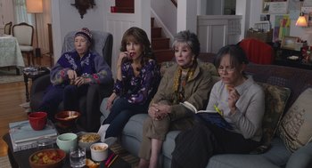 Movie still from “80 for Brady” (2023), directed by Kyle Marvin – A group of women sitting on a couch eating food; Medium shot, High angle