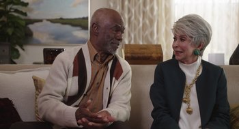 Movie still from “80 for Brady” (2023), directed by Kyle Marvin – An older man and a younger woman sitting in a living room; Medium shot, Over the shoulder angle