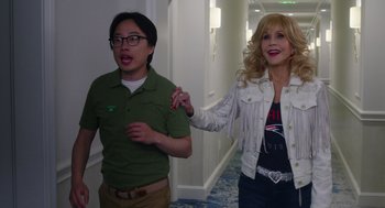Movie still from “80 for Brady” (2023), directed by Kyle Marvin – A man and a woman walking down a hall way; Medium shot, Over the shoulder angle