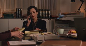 Movie still from “80 for Brady” (2023), directed by Kyle Marvin – A woman sitting at a table talking on a phone; Medium shot, High angle