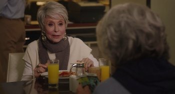 Movie still from “80 for Brady” (2023), directed by Kyle Marvin – A woman sitting at a table with a plate of food; Close Up shot, Over the shoulder angle