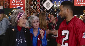 Movie still from “80 for Brady” (2023), directed by Kyle Marvin – A group of people that are standing in a room; Medium shot, Over the shoulder angle