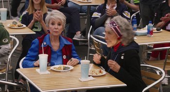 Movie still from “80 for Brady” (2023), directed by Kyle Marvin – Two older women sitting at a table with plates of food; Medium shot, High angle