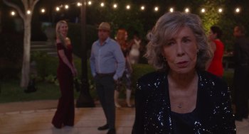 Movie still from “80 for Brady” (2023), directed by Kyle Marvin – A group of people standing in a yard at night; Medium shot, Over the shoulder angle