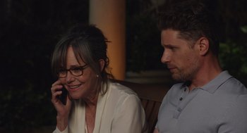 Movie still from “80 for Brady” (2023), directed by Kyle Marvin – A woman talking on a cell phone while sitting next to a man; Close Up shot, Over the shoulder angle