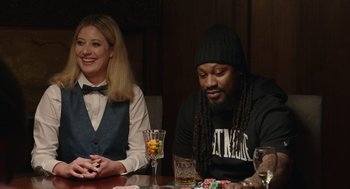 Movie still from “80 for Brady” (2023), directed by Kyle Marvin – A man and woman sitting at a wooden table; Medium shot, Over the shoulder angle