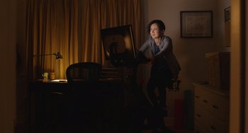 Movie still from “80 for Brady” (2023), directed by Kyle Marvin – A woman standing in front of a computer monitor; Medium shot, Over the shoulder angle