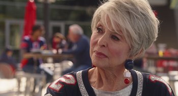 Movie still from “80 for Brady” (2023), directed by Kyle Marvin – An older woman with white blonde hair wearing a silver jacket; Close Up shot, Over the shoulder angle