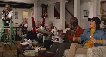 Movie still from “80 for Brady” (2023), directed by Kyle Marvin – A group of people sitting around a living room; Wide shot, High angle