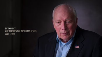 Movie still from “9/11: Inside the President's War Room” (2021), directed by Adam Wishart – An older man wearing a suit and a blue shirt; Close Up shot, High angle