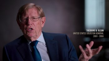 Movie still from “9/11: Inside the President's War Room” (2021), directed by Adam Wishart – An older man wearing a suit and tie talking; Close Up shot, Over the shoulder angle