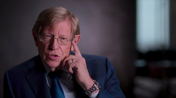 Movie still from “9/11: Inside the President's War Room” (2021), directed by Adam Wishart – An older man in a suit and tie talking on a cell phone; Close Up shot, High angle