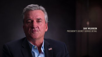 Movie still from “9/11: Inside the President's War Room” (2021), directed by Adam Wishart – An older man wearing a suit and a blue shirt; Close Up shot, Low angle