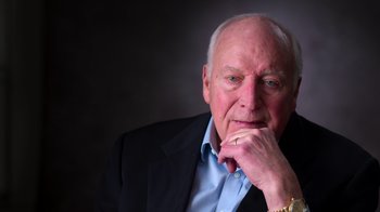 Movie still from “9/11: Inside the President's War Room” (2021), directed by Adam Wishart – An older man wearing a suit and a watch; Close Up shot, Low angle