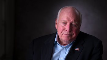 Movie still from “9/11: Inside the President's War Room” (2021), directed by Adam Wishart – An older man wearing a suit and a blue shirt; Close Up shot, Low angle