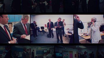 Movie still from “9/11: Inside the President's War Room” (2021), directed by Adam Wishart – A group of men in suits standing in a room; Medium shot, High angle