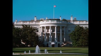 Movie still from “9/11: Inside the President's War Room” (2021), directed by Adam Wishart – A large white building sitting on top of a green field; Extreme Wide shot, Low angle