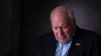Movie still from “9/11: Inside the President's War Room” (2021), directed by Adam Wishart – An older man wearing a suit and a blue shirt; Close Up shot, High angle