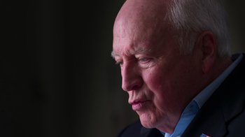 Movie still from “9/11: Inside the President's War Room” (2021), directed by Adam Wishart – An older man in a black suit looking to his left; Close Up shot, Low angle