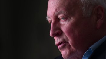 Movie still from “9/11: Inside the President's War Room” (2021), directed by Adam Wishart – An older man looking into the distance with a serious look on his face; Extreme Close Up shot, Low angle