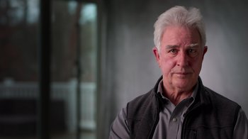 Movie still from “9/11: Inside the President's War Room” (2021), directed by Adam Wishart – An older man with white hair is looking at the camera; Close Up shot, Low angle