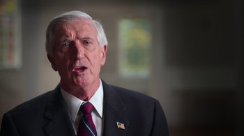 Movie still from “9/11: Inside the President's War Room” (2021), directed by Adam Wishart – An older man wearing a suit and tie; Close Up shot, Low angle