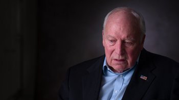 Movie still from “9/11: Inside the President's War Room” (2021), directed by Adam Wishart – An older man wearing a suit and a blue shirt; Close Up shot, Low angle