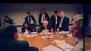Movie still from “9/11: Inside the President's War Room” (2021), directed by Adam Wishart – A group of men sitting at a table in a conference room; Medium shot, High angle