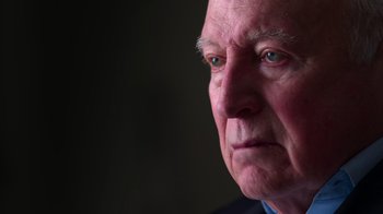 Movie still from “9/11: Inside the President's War Room” (2021), directed by Adam Wishart – An older man with a serious look on his face; Close Up shot, Low angle
