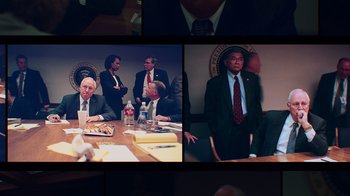 Movie still from “9/11: Inside the President's War Room” (2021), directed by Adam Wishart – A group of men in suits sitting at a conference table; Medium shot, High angle